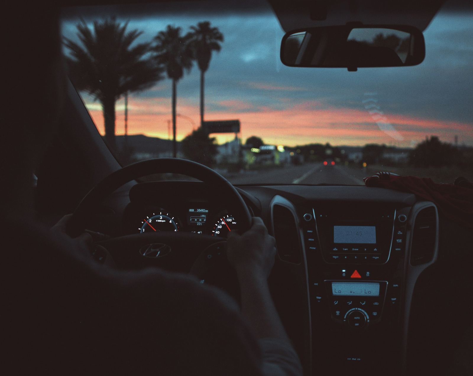 Conductor al volante de noche, con las luces de la ciudad al fondo.